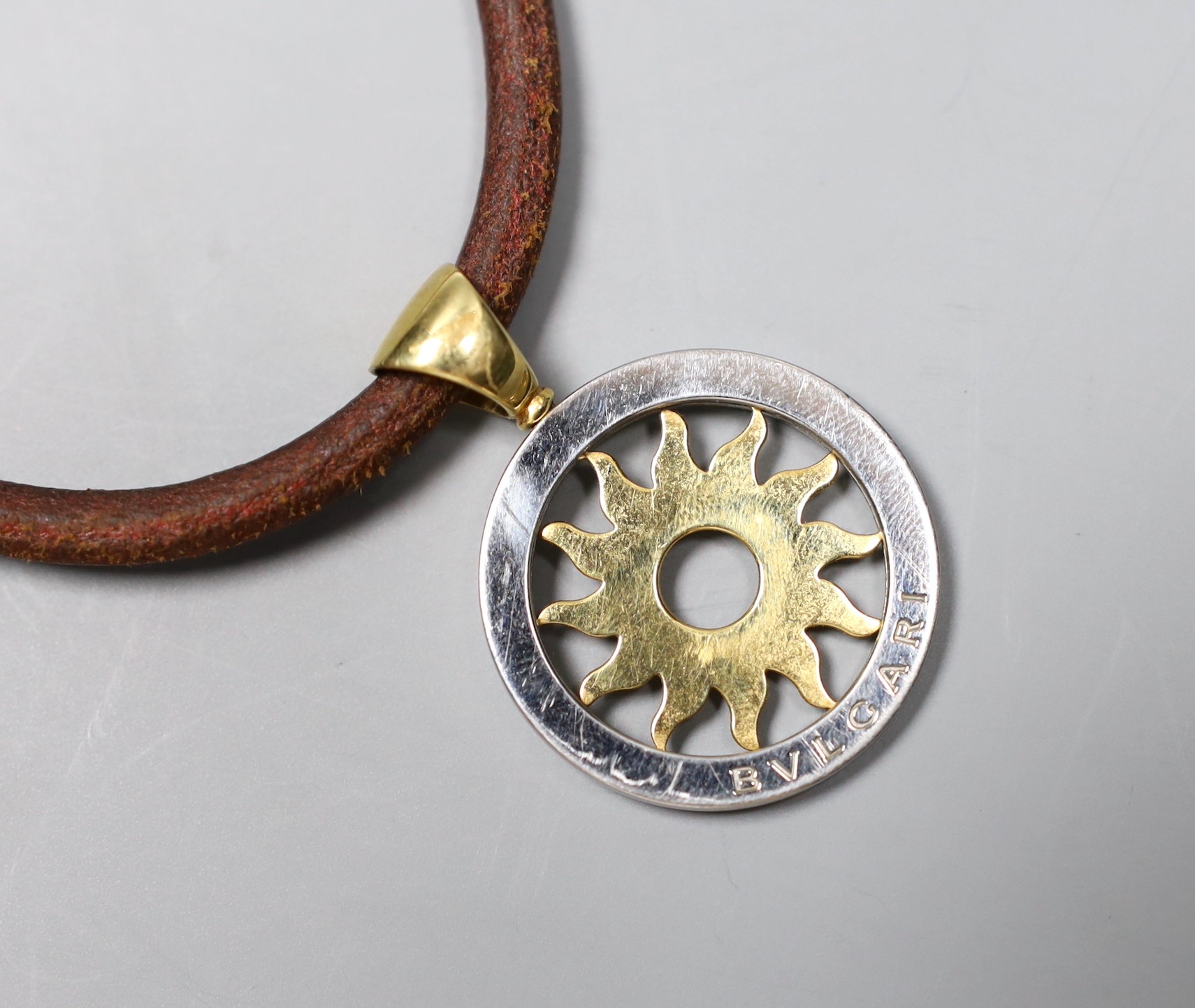A modern Bulgari 18k and steel circular 'sun' pendant, 30mm, on a Bulgari fabric necklet, with 750 clasp, gross weight 27.4 grams.